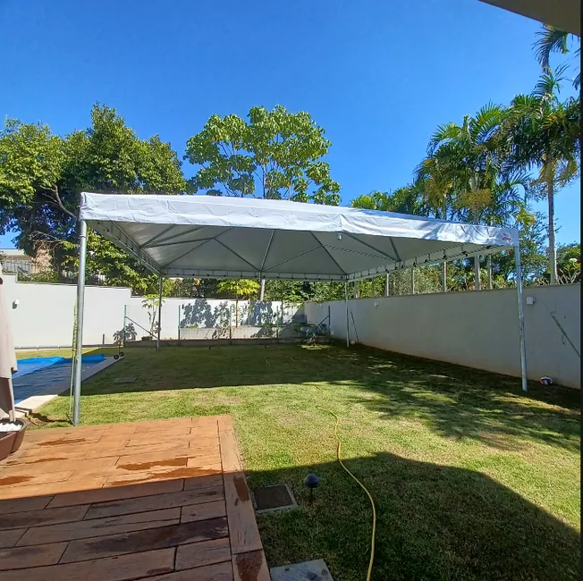 Tenda piramidal branca instalada em jardim residencial com piscina